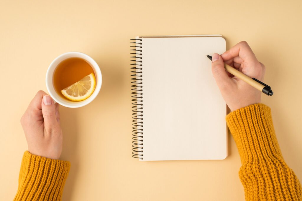 Woman writing in a journal while holding a cup of tea