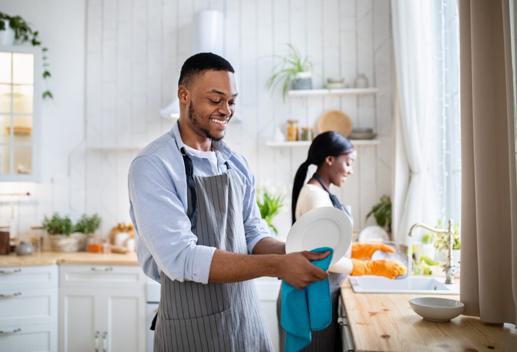 Couple working together washing and drying dishes in the kitchen after a holiday dinner