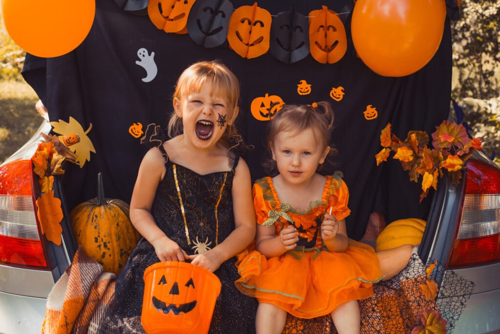 Kids and parents celebrating Halloween with candy at a decorated trunk-or-treat car trunk event